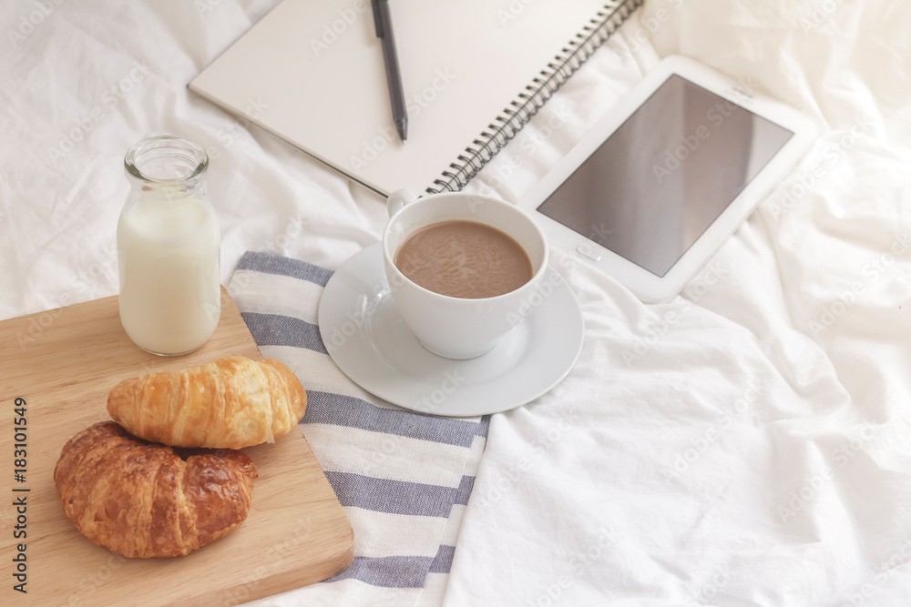 Simple workspace or coffee break in morning. cup of hot coffee, croissant and book on working table in the morning. Simple workspace or coffee break in morning. cup of hot coffee, croissant and book on working table in the morning.