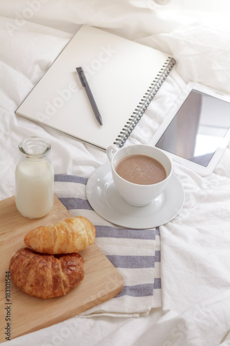 Simple workspace or coffee break in morning. cup of hot coffee, croissant and book on working table in the morning.