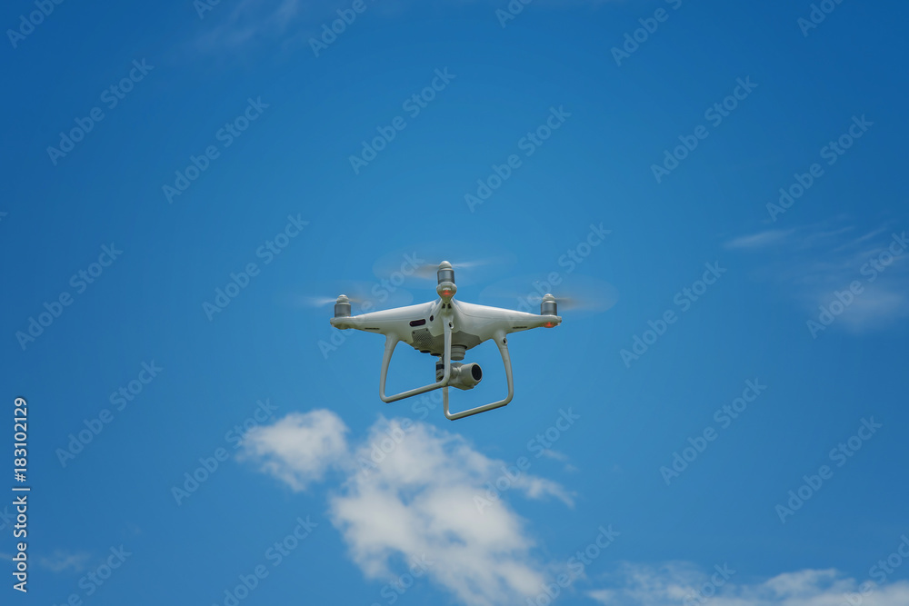 white drone hovering in a bright blue sky white drone hovering in a bright blue sky