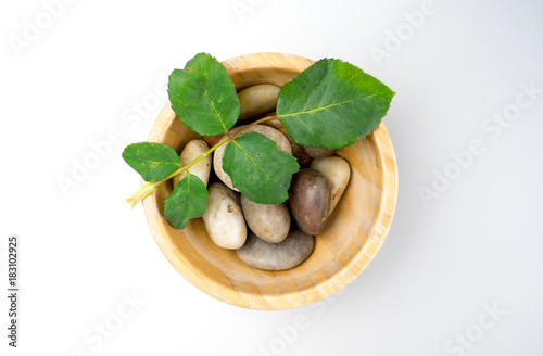 Top view of spa stones and green leaves in wooden bowl