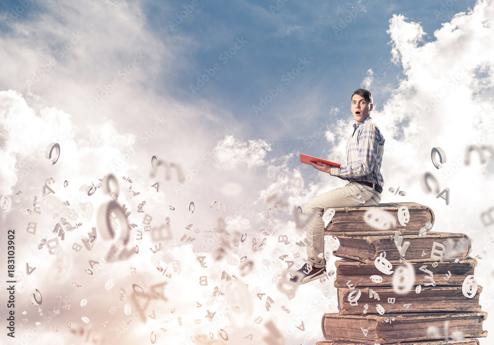 Man student on stack reading book and symbols flying around Man student on stack reading book and symbols flying around