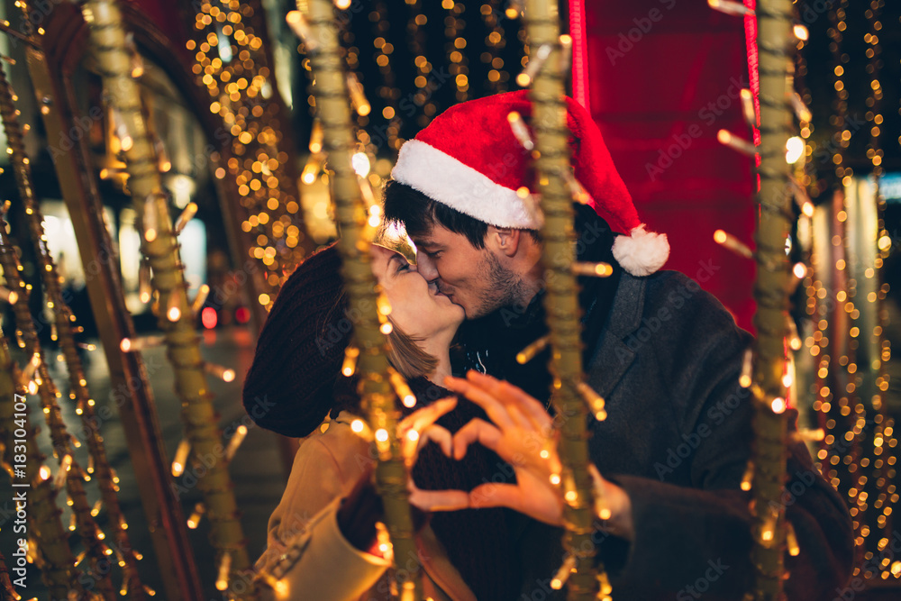Beautiful young couple in love enjoying Christmas or New Year night on a city street. 