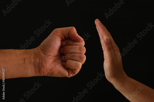 Image of male fist and female hand showing STOP. Domestic violence concept against women. photo