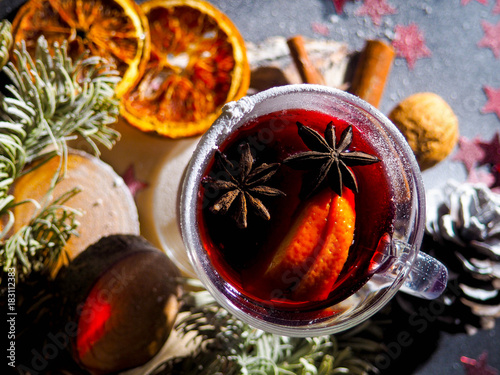 Christmas mulled wine with spices in glasswith plaid and snow on a christmas tree on dark background, The glass cup of hot winter drink