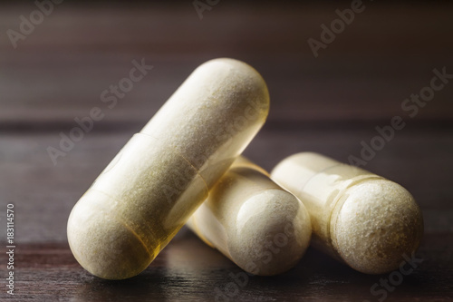 White capsules of glucosamine chondroitin, healthy supplement pills on wooden table, macro image photo