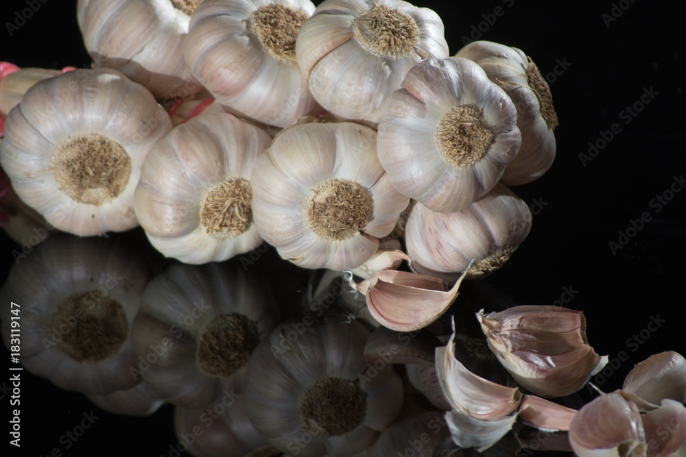 String of french pink garlic on old tin plate on black background