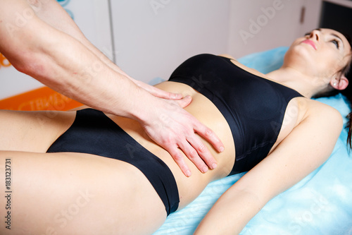 the hands of a masseur make a relaxing massage to a woman on the abdominal abdomen for toning the muscles. Close-up