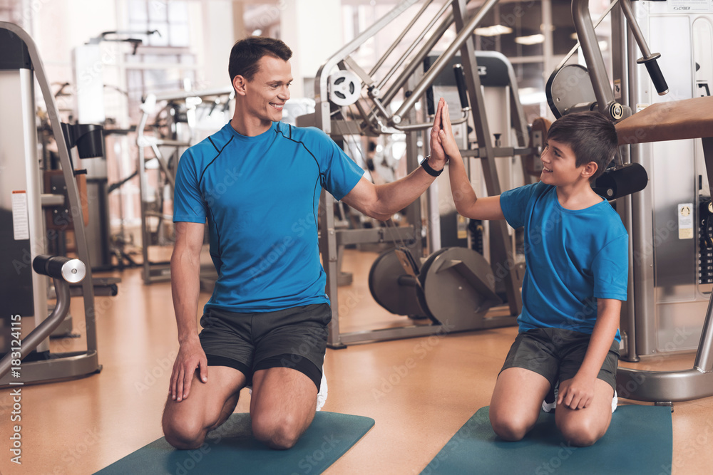 Dad and son in the same clothes in gym. Father and son lead a healthy lifestyle. Dad and son in the same clothes in gym. Father and son lead a healthy lifestyle.