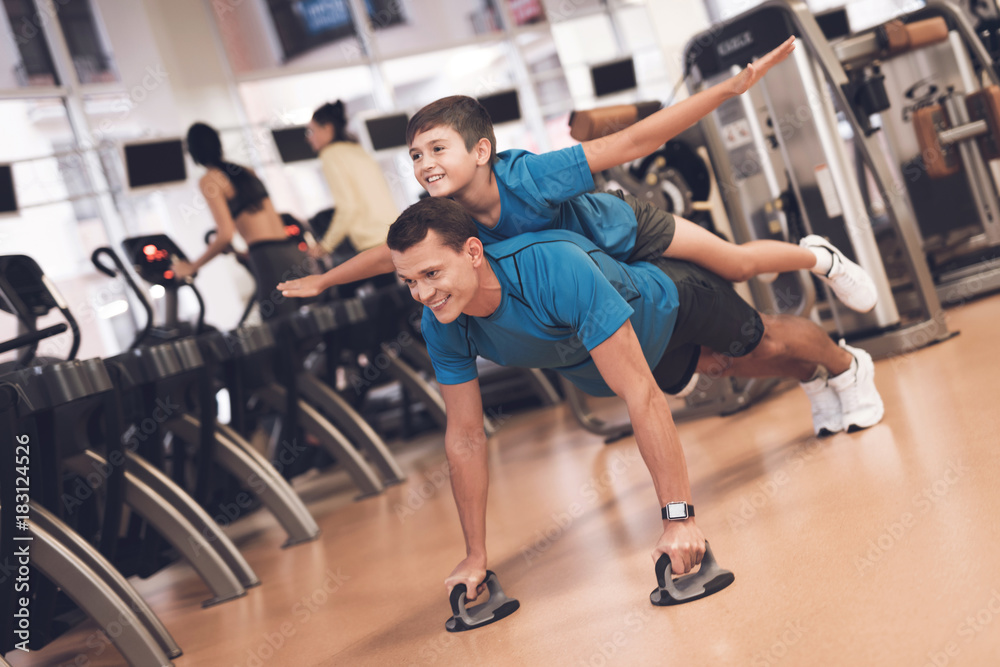 Dad and son in the same clothes in gym. Father and son lead a healthy lifestyle. Dad and son in the same clothes in gym. Father and son lead a healthy lifestyle.