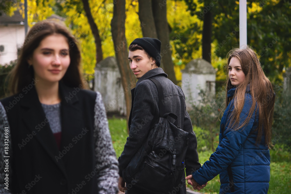 Disloyal man with his girlfriend and looking amazed at another seductive girl Disloyal man with his girlfriend and looking amazed at another seductive girl