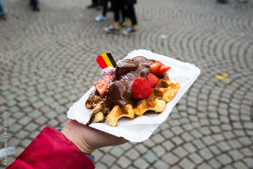 Fototapeta premium Belgium waffle with chocolate sauce and strawberries, Bruges city background