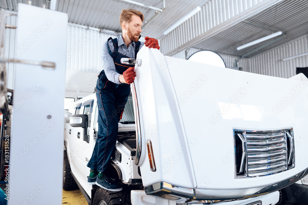 Red-haired man works at the auto service. The mechanic is engaged in repairing the car. Red-haired man works at the auto service. The mechanic is engaged in repairing the car.