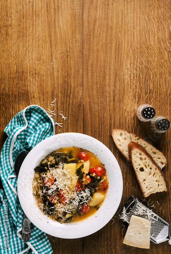 Curly kale (or cavolo nero) and barley soup. Winter Vegetable Soup on a wooden table and fresh homemade bread