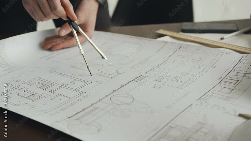 Close-up of mens hands of the of an engineer holding a compass and working on a new apartment construction project. Engineers workplace