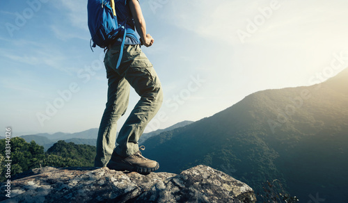 successful female backpacker enjoy the view cliff's edge