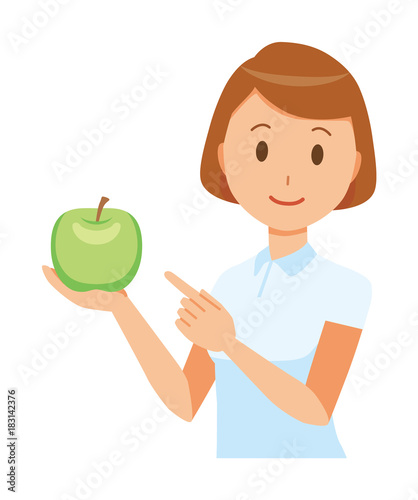 A female nurse wearing a white uniform has a green apple