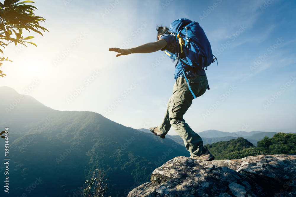 brave woman hiker walking to the cliff edge on mountain top