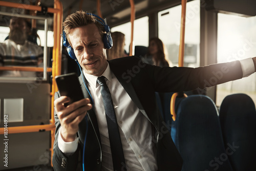 Young businessman listening to music while riding on a bus