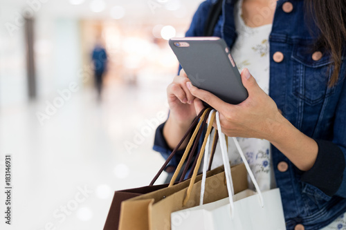 Woman use of smart phone and holding carry paper bags