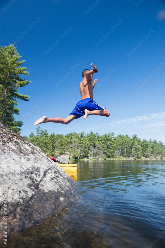 Ethnic kids jumping into the river during a camping trip Ethnic kids jumping into the river during a camping trip