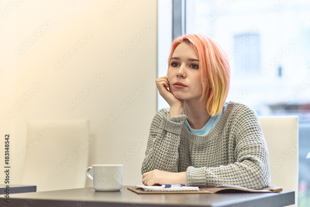 lonely bored young girl sitting at a table in a cafe, leaning her head on  his hand with a sad upset depressed expression Stock Photo | Adobe Stock