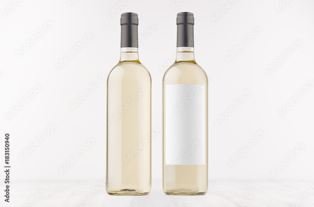 Two transparent wine bottles with blank white label and without label, on white wooden board, mock up. Template for advertising, design, branding identity.
