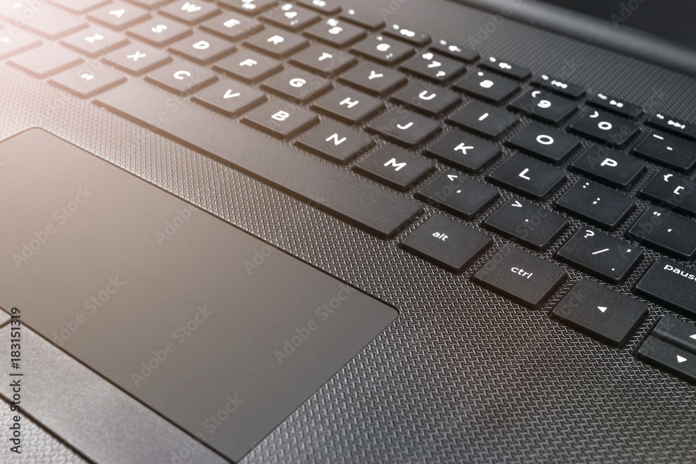 Close up view of a modern laptop computer keyboard keys and track pad. Soft lightning