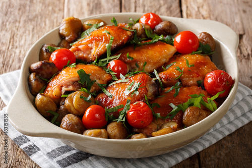 Spicy roast chicken with chestnuts, greens and tomatoes close-up in a dish. horizontal