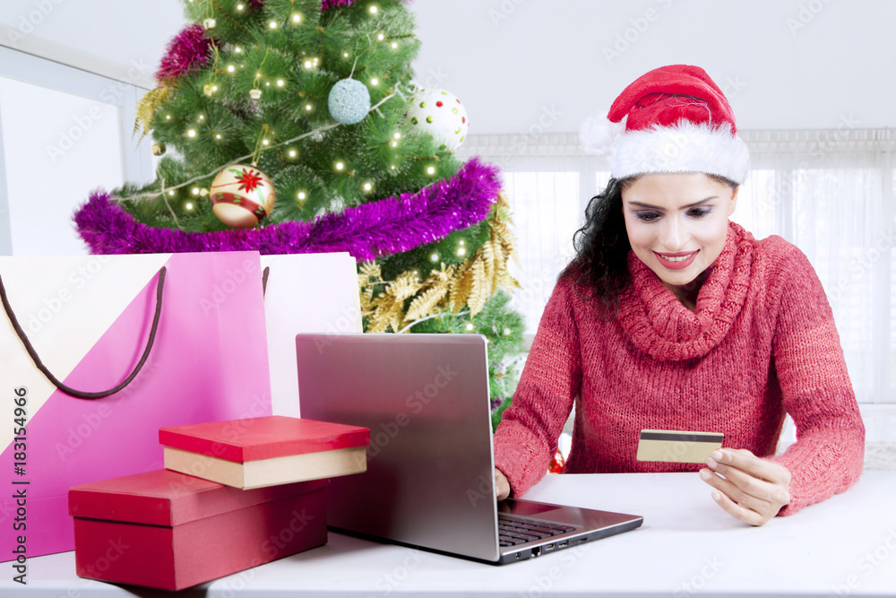 Pretty girl holds credit card near Christmas tree Pretty girl holds credit card near Christmas tree