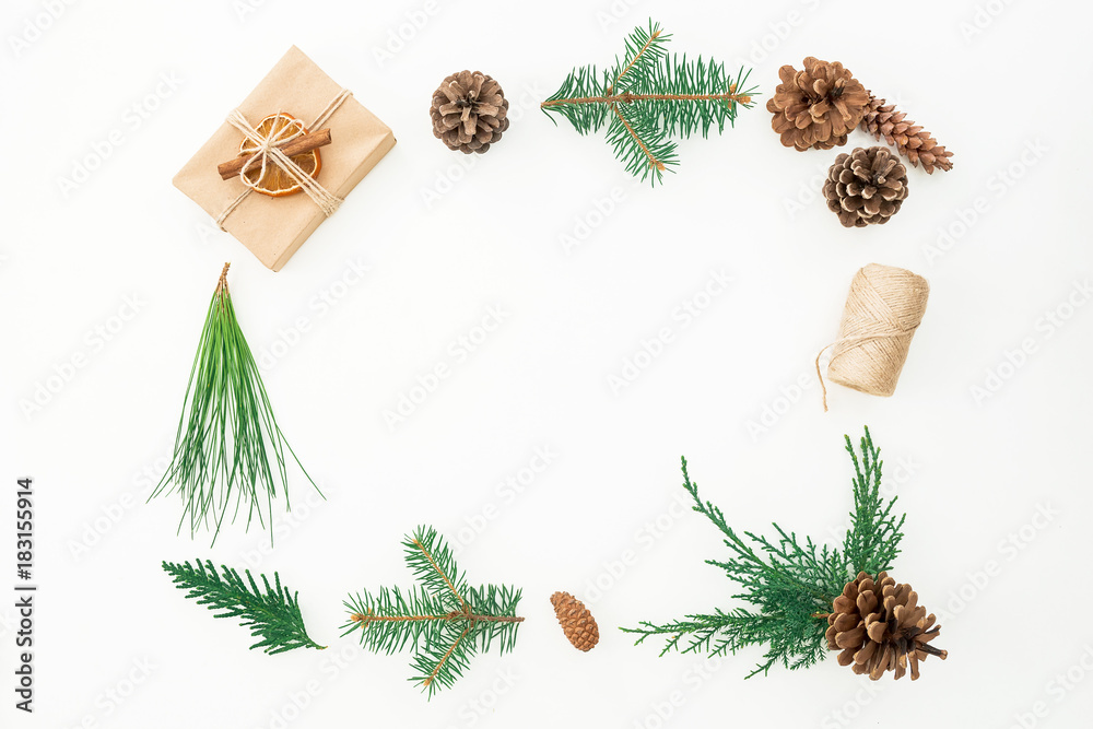 Christmas frame of gift, branches of winter tree and pine cones on white background. Flat lay. Top view
