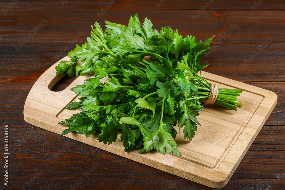 A bunch of green parsley on a wooden table. A bunch of green parsley on a wooden table.