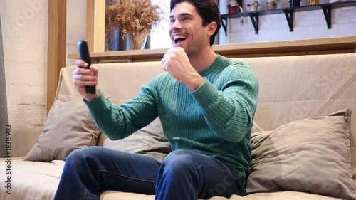 Man Celebrating Online Success while Watching Match on TV photo