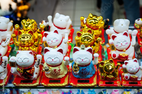 Chinese. Japanese souvenirs. Figurine white and golden cats brings good luck. Golden Maneki Neko cat or Welcome mascot © eteri