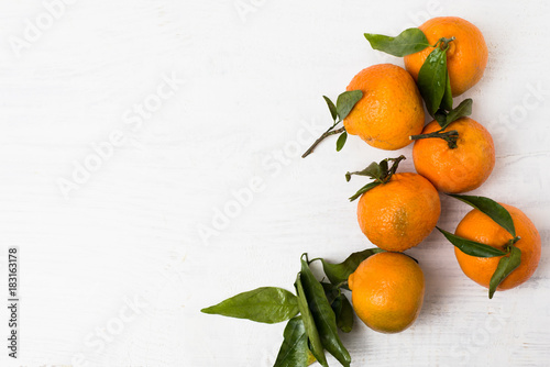 Fresh, ripe, organic mandarin oranges, clementines or tangerines with stems and leaves still wet with water drops on white wooden background, untreated mandarines with little blemishes, freshly picked © Corinna Haselmayer