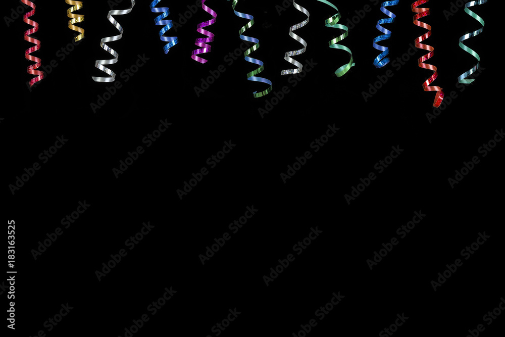 Horizontal image with multi coloured rolls curly ribons hanging from the top on black bacgroung Horizontal image with multi coloured rolls curly ribons hanging from the top on black bacgroung