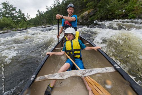 Young boy paddling whitewater in a canoe photo