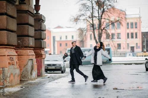 Young beautiful couple jumping through the city. Winter love story, a beautiful stylish young couple. Winter fashion concept with boyfriend and girlfriend.