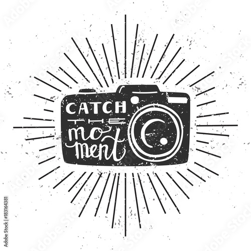 Catch the moment. Vector illustration with black silhouette of photo camera with hand written quote, scroll and sunburst on white background with grunge texture. 