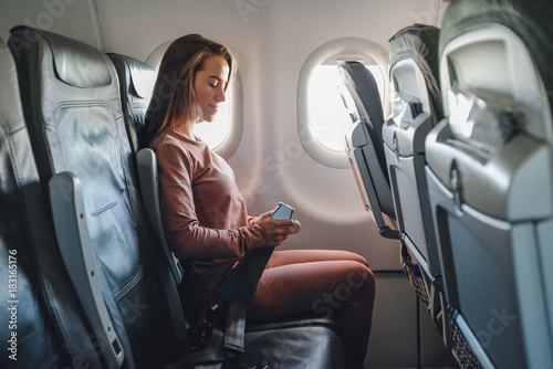 Girl is strapped on the plane near window
