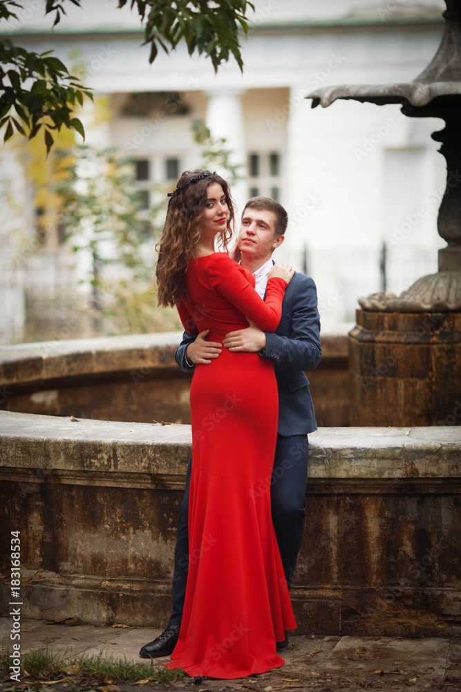 Beautiful guy and girl in front of an ancient fountain