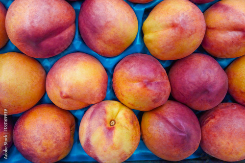 A pile of nectarines in the package in supermarket  background 