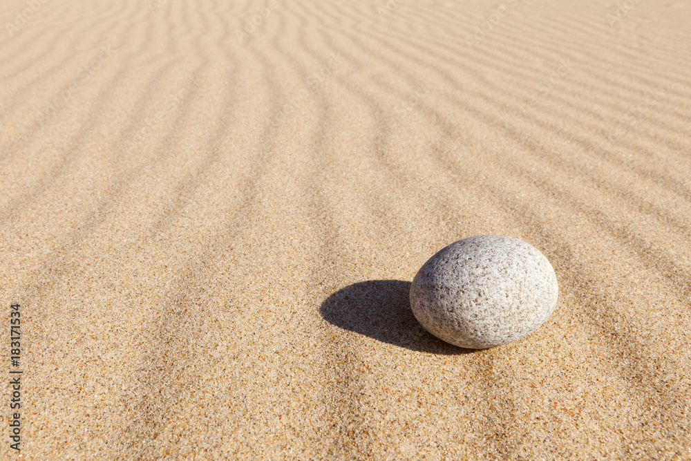 White round stone lying on clean sand. Concept of balance, harmony and meditation. Minimalism White round stone lying on clean sand. Concept of balance, harmony and meditation. Minimalism