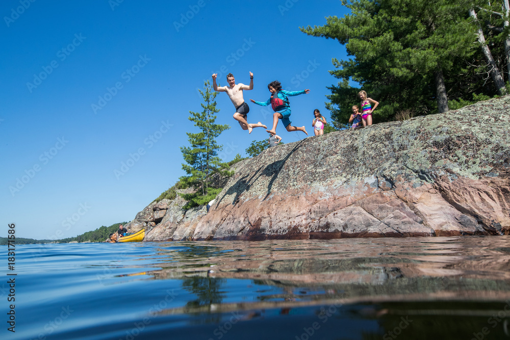 Ethnic kids jumping into the river during a camping trip