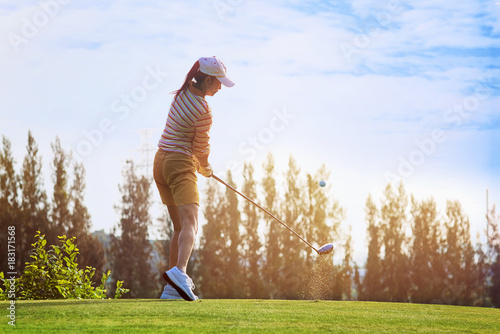 Fluffing of golf ball and tee flying away from the teeing ground impact by the woman golfer player after swing plane of proper stance addressing the ball