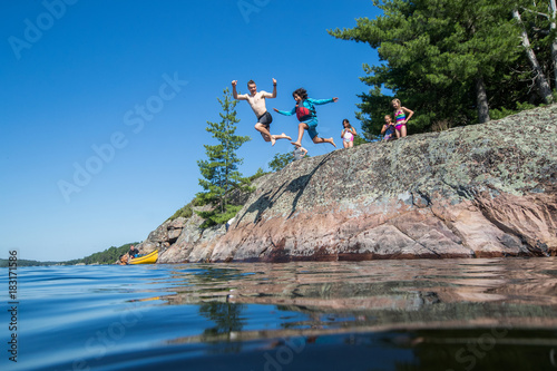 Obraz na płótnie Ethnic kids jumping into the river during a camping trip w salonie