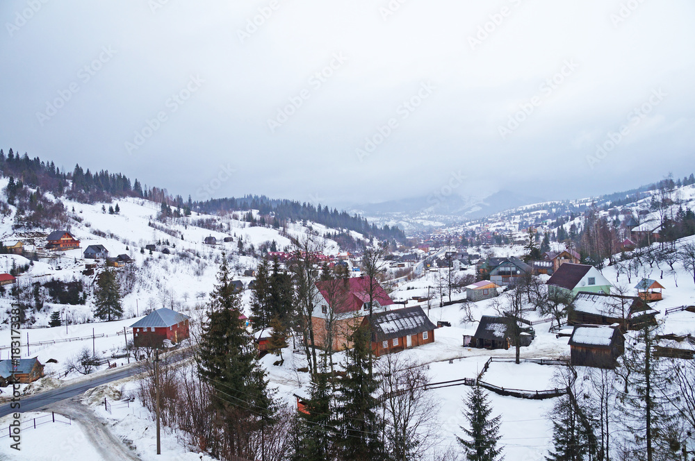 Winter has enveloped the mountain village in the Carpathians of Ukraine. Small houses in a snowy mountain valley in the Ukrainian Carpathians. Winter in the Ukrainian Carpathians.