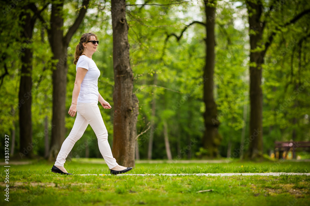 Middle-aged woman walking in city park Middle-aged woman walking in city park
