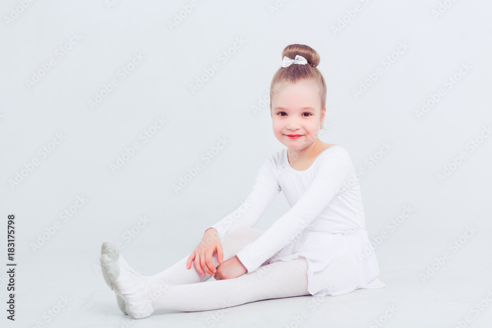 Little child girl dance ballet at white background. Portrait of small ballerina smiling and looking at camera Little child girl dance ballet at white background. Portrait of small ballerina smiling and looking at camera