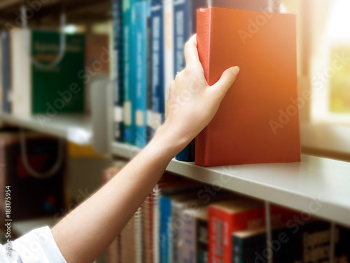 Asian Woman at the library, she is searching books on the bookshelf with selective focus