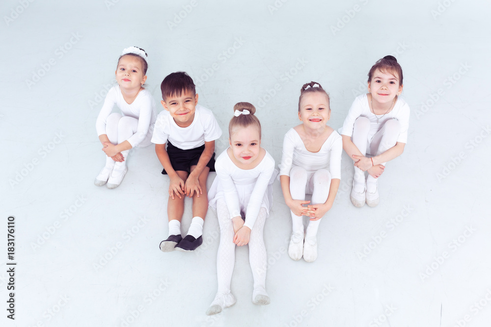 Naklejka premium Cute little kids dancers on white background. Choreographed dance by a group of small ballerinas practicing at a classical ballet school